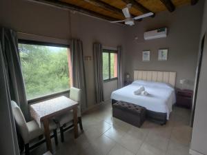 a bedroom with a bed and a table and a window at Posada Abrazo Serrano en Carpintería in Carpintería