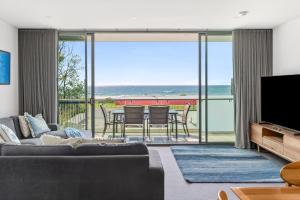a living room with a couch and a television at The Dolphin Apartments in Apollo Bay