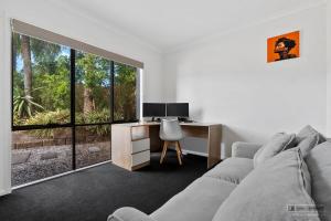a living room with a couch and a desk with a computer at Maison De Vacances in Banksia Beach
