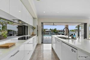 a kitchen with white cabinets and a view of a pool at Maison De Vacances in Banksia Beach