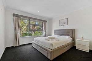 a white bedroom with a bed and a window at Maison De Vacances in Banksia Beach +23 photos