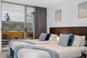 two beds in a hotel room with a window at The Dolphin Apartments in Apollo Bay