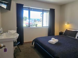 a bedroom with a bed and a sink and a window at The Highway Inn in Christchurch +4 photos