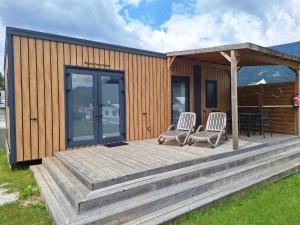 a small house with two chairs and a deck at Mobile Home in Austrian Countryside in Altossiach
