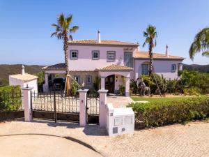a house with a gate and palm trees at Private Bedroom in a Luxurious Villa, Budens in Budens