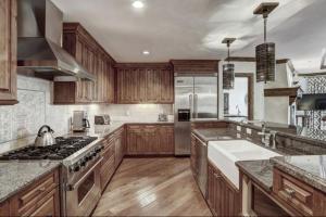 a large kitchen with wooden cabinets and stainless steel appliances at Platinum 4 Bedroom Vacation Rental In The Heart Of Vail That Includes Ski Valet, Ski Deck, Rooftop Pool, Panoramic Views in Vail