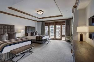 a large bedroom with two beds and a television at Platinum 4 Bedroom Vacation Rental In The Heart Of Vail That Includes Ski Valet, Ski Deck, Rooftop Pool, Panoramic Views in Vail