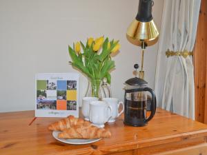 a table with croissants and a coffee maker and a lamp at Cotterton Beag in Nethy Bridge