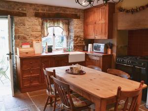 a kitchen with a wooden table with chairs and a stove at Corner Cottage in Bakewell