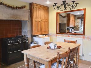 a kitchen with a wooden table with chairs and a mirror at Corner Cottage in Bakewell