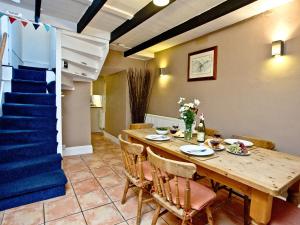 a dining room with a table and a blue staircase at Pilgrims Cottage in Brixham