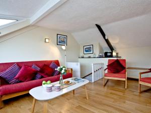 a living room with a red couch and a table at Pilgrims Cottage in Brixham