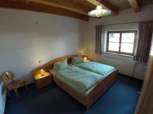 ein Schlafzimmer mit einem Bett, einem Stuhl und einem Fenster in der Unterkunft Apartments Wolf in Reutte
