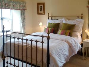 a bedroom with a large bed with white sheets and pillows at Corner Cottage in Bakewell +5 photos