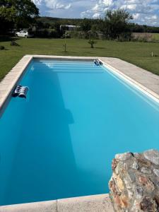 a swimming pool with blue water and a stone wall at Casa de verano confortable in Villa Las Rosas