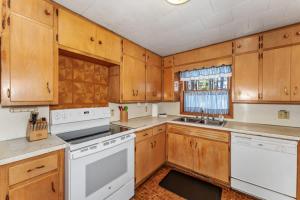 a kitchen with wooden cabinets and white appliances at Eagle Villa At Otter Cove in Eagle River +26 photos