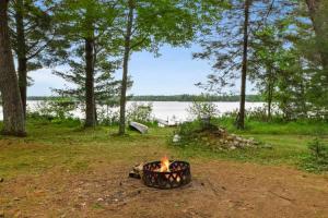 a fire pit in the grass next to a lake at Creekside Big St Germain Lake in Saint Germain
