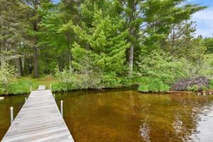 a wooden dock on a river with trees at Creekside Big St Germain Lake in Saint Germain