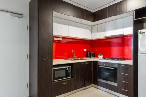 a kitchen with red walls and brown cabinets at Central 2BR Apt by Melbourne Central City Views in Melbourne