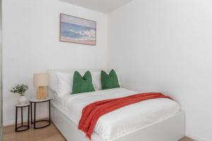 a white bedroom with a bed with green pillows at Central 2BR Apt by Melbourne Central City Views in Melbourne