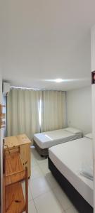 a room with two beds and a table in it at Maragogi Hostel in Maragogi