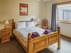 a bedroom with a wooden bed and a window at Cotterton Beag in Nethy Bridge