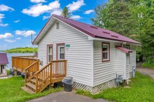 a white tiny house with a porch and a deck at TB5 Thunder Bay Resort Cabin5 in Phelps