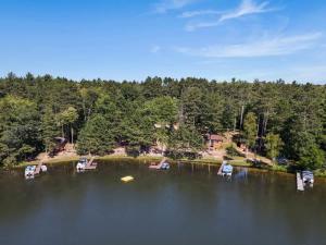 a group of chairs on a lake with trees at Bayview Resort Waters Edge Cabin 2 in Saint Germain