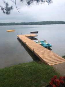 a dock with a boat sitting on top of a lake at Bayview Resort Sandy Shores Cabin 3 in Saint Germain