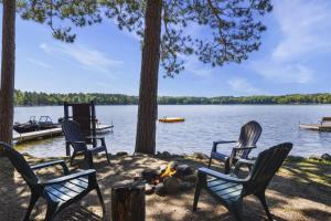 a person laying on the ground in chairs next to a lake at Bayview Resort Sandy Shores Cabin 3 in Saint Germain