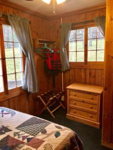 a bedroom with a bed and a dresser and windows at Bayview Resort Sandy Shores Cabin 3 in Saint Germain