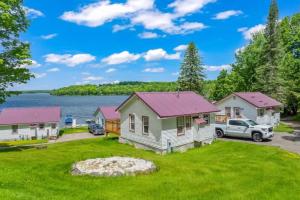 a house with a truck parked in front of a lake at TB6 Thunder Bay Resort Cabin 6 in Phelps