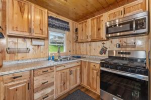 a kitchen with wooden cabinets and a stove top oven at TB3 Thunder Bay Resort Cabin 3 in Phelps