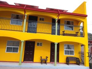 a yellow building with a balcony and two benches at Hotel Ecológico Temazcal in Creel