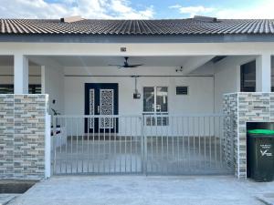 a white house with a gate and a fence at Amara Homestay Gurun in Kampong Bongkok