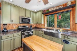 a kitchen with green cabinets and a sink and a stove at Clover Pines in Eagle River