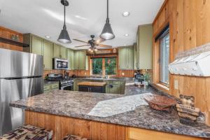 a kitchen with green cabinets and a stainless steel refrigerator at Clover Pines in Eagle River +24 photos