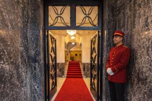 a man in uniform standing in a doorway with a red carpet at Casa Figueroa - Boutique Hotel- Adults Only in Cairo
