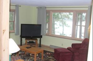 a living room with a flat screen tv and two windows at Bayview Resort Sunset Lookout Cabin 6 in Saint Germain