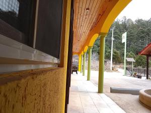 an empty building with yellow and yellow columns and a sidewalk at Hotel Ecológico Temazcal in Creel