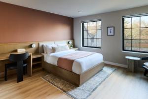 a bedroom with a bed and a desk and two windows at The Dylin in Madison