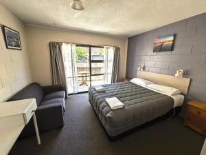 a bedroom with a bed and a couch and a window at Judges Pool Motel Turangi in Turangi