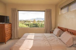 a bedroom with a bed and a large window at Arrowtown Dress Circle in Arrowtown