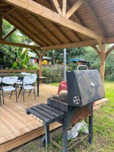 a grill and a picnic table under a pavilion at Maison de campagne proche des plages in Sainte-Rose