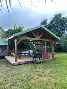 a wooden gazebo with tables and chairs in a field at Maison de campagne proche des plages in Sainte-Rose
