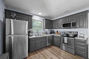 a kitchen with gray cabinets and a stainless steel refrigerator at New Spacious Renovated Townhouse in Spring Hill