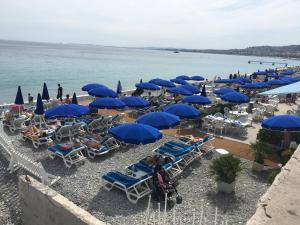 a beach with blue umbrellas and chairs and the ocean at Olma in Nice