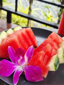 a plate with a flower and slices of watermelon and a purple flower at Walden Moon Resort in Ko Lanta Yai +20 photos