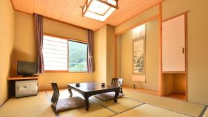 a living room with a table and chairs and a television at Bouzantei Kotobuki in Ueda