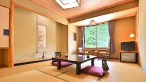 a living room with a table and a dining room at Bouzantei Kotobuki in Ueda